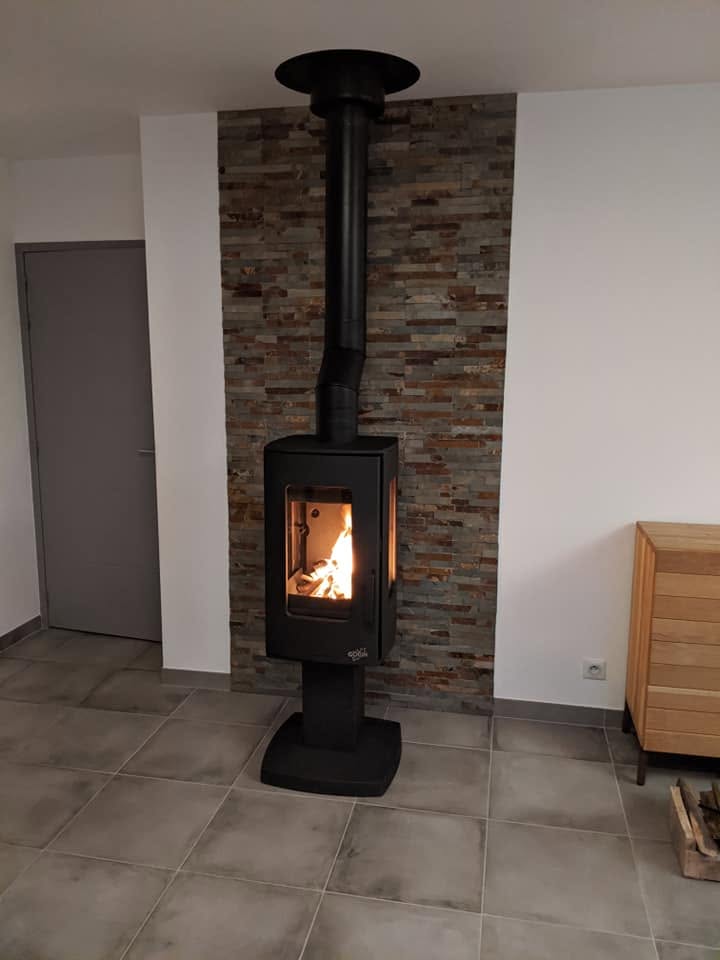 Poêle à bois installé devant un parement en pierre